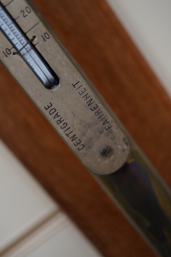 A 20th century lacquered brass marine stick barometer and thermometer by A. Gallenkamp & Co. Ltd., London, with a silvered scale, mounted on a faded oak plaque, 107cm high overall